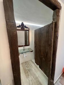 baño con puerta de madera, lavabo y espejo en Casa Lourdes, en Santa Cruz de la Palma