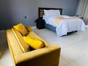 a bedroom with a yellow couch and a bed at Kaste Guest House Edenvale in Edenvale +22 photos
