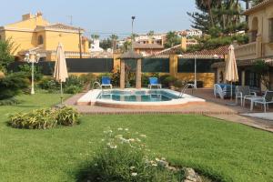 a backyard with a pool with two chairs and umbrellas at Casa Beatriz in Rincón de la Victoria