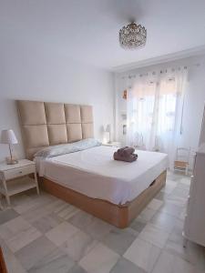 a white bedroom with a large bed and a chandelier at Casa Beatriz in Rincón de la Victoria