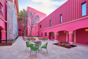 オアハカにあるCity Centro by Marriott Oaxacaのピンクの建物を利用した中庭(テーブル、椅子付)