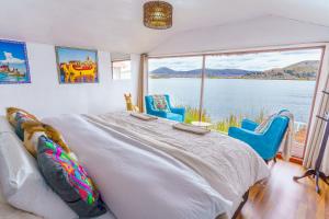 a bedroom with a bed and chairs and a large window at Titicaca Uros Summa Paqari in Uros
