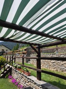 a green and white canopy over a stone fence at Baita LE SERE in Sestriere