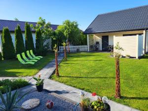 een tuin met groene stoelen en een huis bij Domki Na Kasztanowej in Rewal