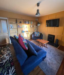 sala de estar con sofá azul y TV en Caretaker’s Cottage, 