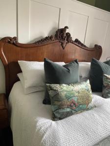 a bed with a wooden headboard and pillows on it at Caretaker’s Cottage 