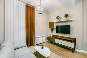 a living room with a couch and a flat screen tv at Sabah residance one bedroom in Baku