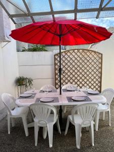 a table with a red umbrella and white chairs at Maison centre Lamotte Beuvron in Lamotte-Beuvron