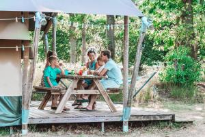 eine Familie, die an einem Picknicktisch in einem Pavillon sitzt in der Unterkunft Glamping Holten luxe safaritent 1 in Holten