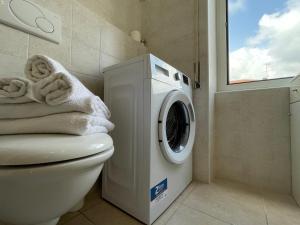 een badkamer met een wasmachine naast een toilet bij [50 metri dal Mare] Trilocale in Centro con A/C in Loano