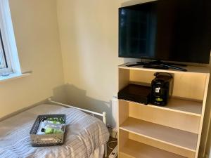 a bedroom with a tv on a stand with a bed at Single bed Parking Internet Coffee Garden Patio TV Quiet Close to main bus route B98 9NH in Beoley