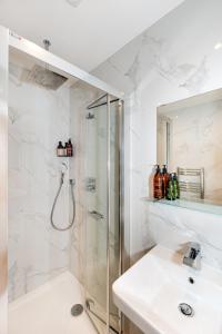 een witte badkamer met een douche en een wastafel bij 2-Bedroom Victorian Apartment in Kensington in Londen