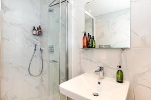 een witte badkamer met een wastafel en een douche bij 2-Bedroom Victorian Apartment in Kensington in Londen