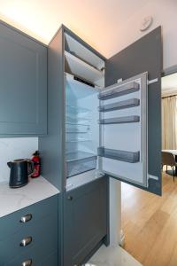 a blue kitchen with an empty refrigerator in it at 2-Bedroom Victorian Apartment in Kensington in London