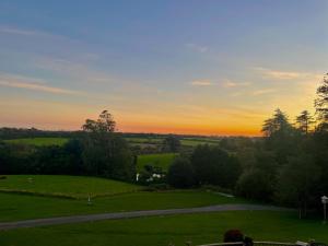 um pôr-do-sol sobre um campo verde com uma estrada em Court Colman Manor em Bridgend