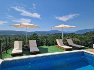 a swimming pool with two umbrellas and chairs next to a swimming pool at La Mer Apartments Kotor in Kotor