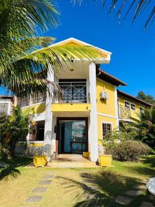 une maison jaune avec un palmier devant elle dans l'établissement Pousada Alto da Colina, à Conservatória