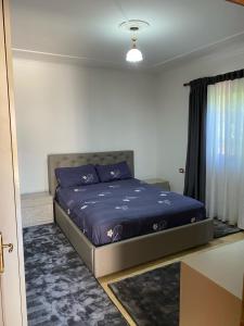 a bedroom with a bed with purple sheets and a window at Vavla House in Berat