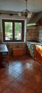 una cucina con pavimento piastrellato, tavolo e finestre di Apartma Brina 3 a Sežana