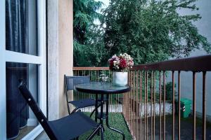 una mesa y sillas en un balcón con un jarrón de flores en LILIENBLUM CHIC Apartment ChicLife - Borgo Santa Caterina, en Bérgamo