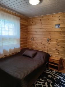 ein Schlafzimmer mit einem Bett in einem Zimmer mit Holzwänden in der Unterkunft VILLA OLGA in Tahkovuori