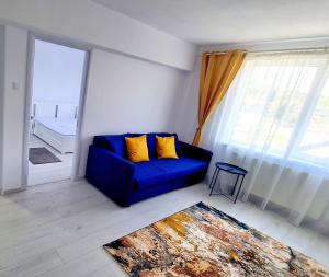 Sofá azul en una habitación con ventana grande en Belle Apartments - Central, en Piteşti