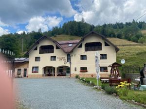 a large white building with a hill in the background at Pensiune Agroturistică Casa Alex in Baba