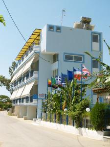 un bâtiment bleu avec drapeaux devant lui dans l'établissement La Fontaine Apartments, à Kandia