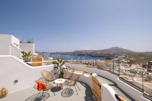 a balcony with chairs and tables and a view of a city at CABO ESTE SUITES in Akrotiri
