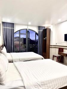 two beds in a hotel room with a large window at Shine Hotel in Hue +33 photos