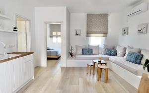 een witte woonkamer met een bank en een tafel bij Anita Rooms & Suites Milos in Adamas
