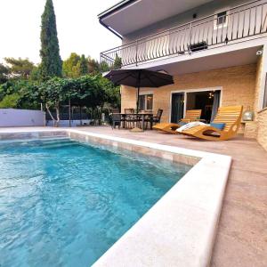 a swimming pool with chairs and a table and a house at Villa Brajkovic in Rovinj