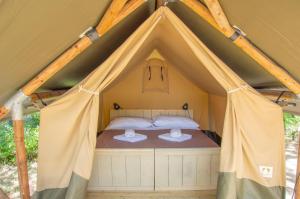 a bed in a tent with curtains around it at Luxor Chianti Glamping village in Castellina in Chianti