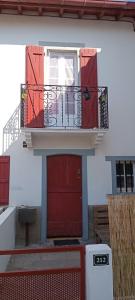 um edifício com duas portas vermelhas e uma varanda em logement entier 5 personnes em Irissarry