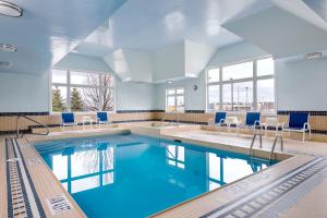a pool with blue water and chairs in a building at Four Points by Sheraton Barrie in Barrie