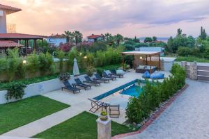 a backyard with a pool and chairs and a house at Selia Villa Pefkochori in Pefkochori