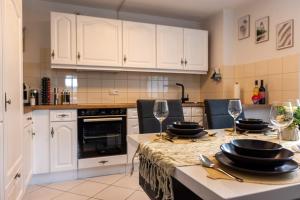 una cocina con armarios blancos y una mesa con copas de vino en Hegau-Refugium: Am Bodensee & der Schweizer Grenze en Singen