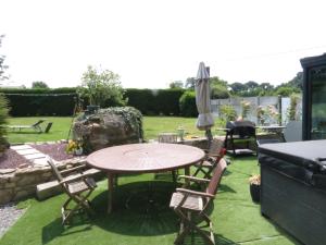 eine Terrasse mit einem Tisch, Stühlen und einem Sonnenschirm in der Unterkunft chambre d’hôte naturiste ou pas in Miniac-Morvan