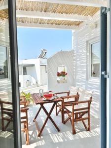 een patio met een houten tafel en stoelen bij Anita Rooms & Suites Milos in Adamas