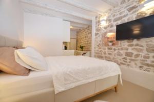 een witte slaapkamer met een stenen muur bij Apartment Al Pozzo in Rovinj
