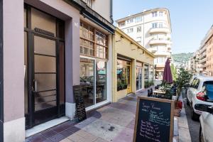 a street with shops and a sign on the sidewalk at SMARTBNB - Appartement 2 pieces LUXE - Climatisé - ACROPOLIS in Nice