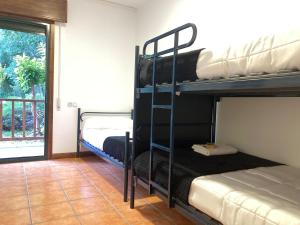 two bunk beds in a room with a window at Albergue O Beque in Moaña