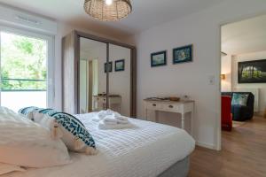 een slaapkamer met een wit bed en een spiegel bij Îlots Dido - Appt proche de la mer in Concarneau