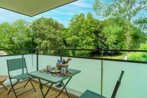 een tafel en stoelen op een balkon met bomen bij Îlots Dido - Appt proche de la mer in Concarneau