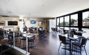 a dining room with tables and chairs and windows at Palm Beach Hotel in Gold Coast