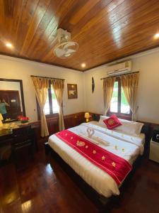 a bedroom with a large bed with a wooden ceiling at Golden Lotus Boutique Hotel in Luang Prabang