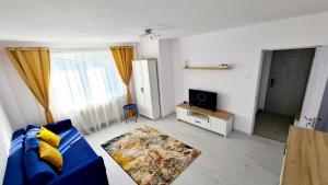 a living room with a blue couch and a tv at Belle Apartments - Central in Piteşti