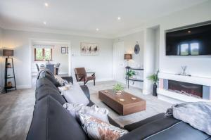 a living room with a black leather couch and a fireplace at Springfield Lodge - 3 Bedroom Home - Princes Gate in Pembrokeshire