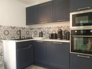 eine Küche mit dunkelblauen Schränken und Geräten in der Unterkunft L'art et Deco RerC-n104-A6-A10 in Brétigny-sur-Orge