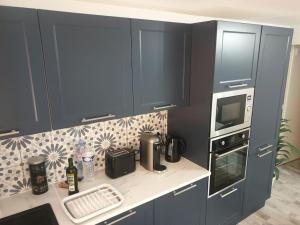 a kitchen with blue cabinets and a white counter top at L'art et Deco RerC-n104-A6-A10 in Brétigny-sur-Orge
